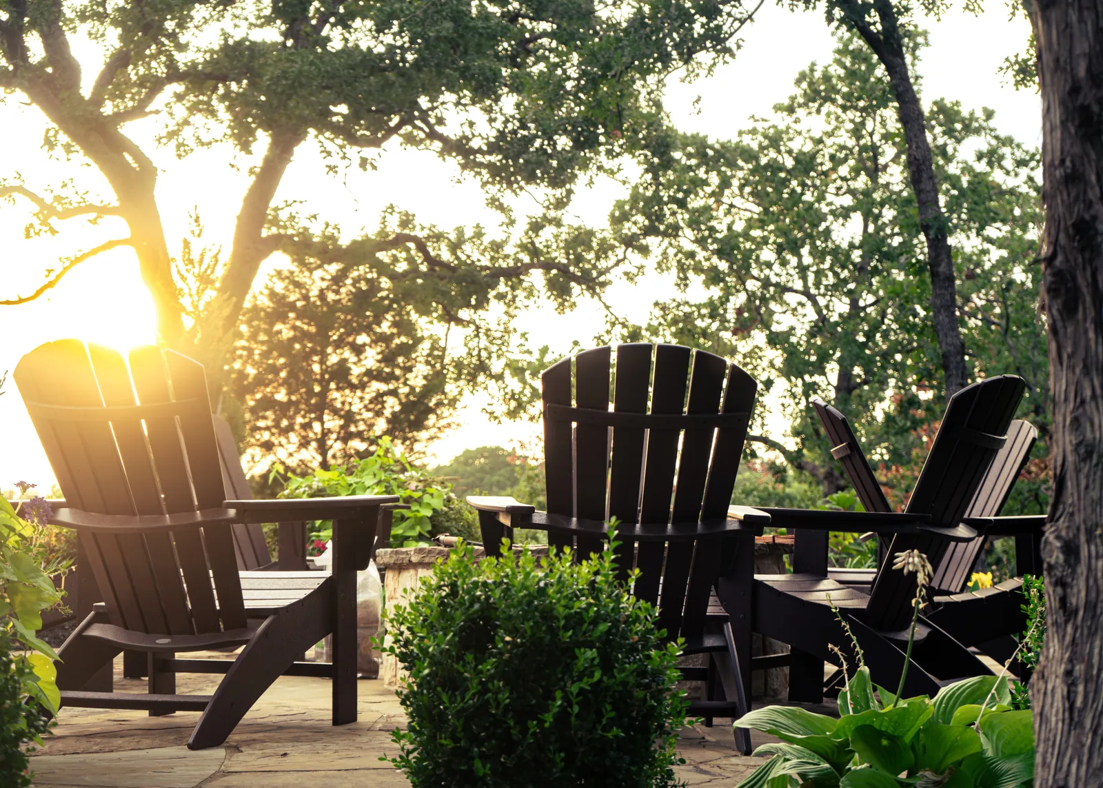Adirondack chairs around a backyard fire pit at sunset framed by mature trees by Greenview Landscaping in Fort Worth
